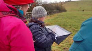 Two people in a field writing on a sheet during training on Curlew habitat assessment