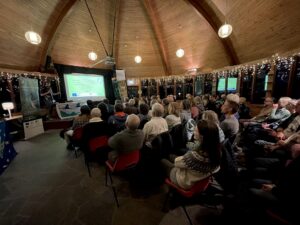 A hall full of people looking towards a speaker at the front, Thijs Claes, project officer for Curlew LIFE at RSPB Insh Marshes, at the Waders Welcome event in March 2023.